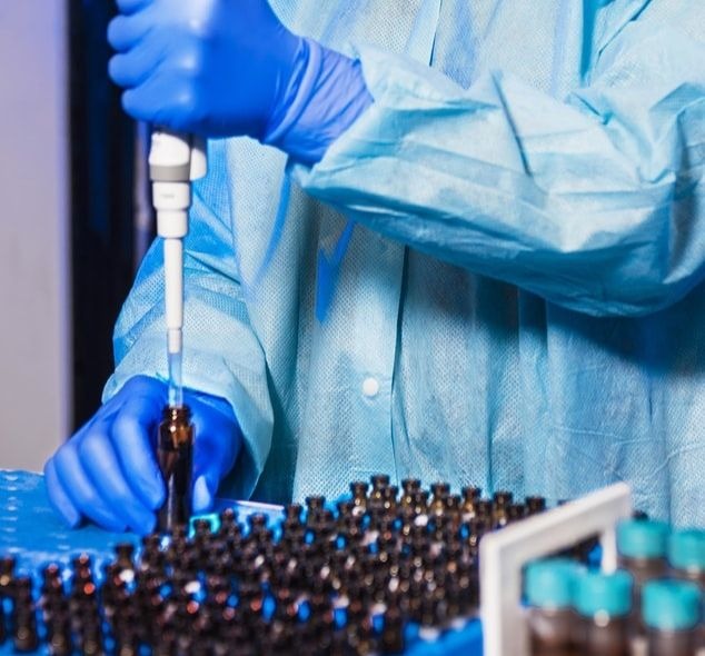 Une chercheuse manipulant des tubes et une séringue dans un laboratoire.