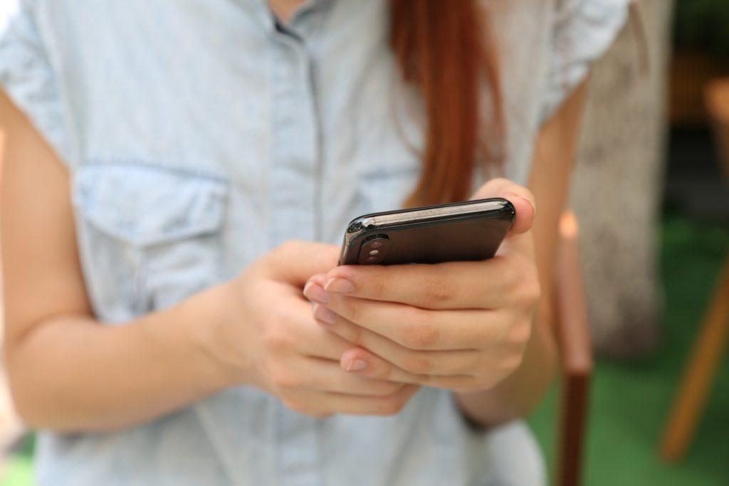 Une jeune femme manipulant son smartphone.