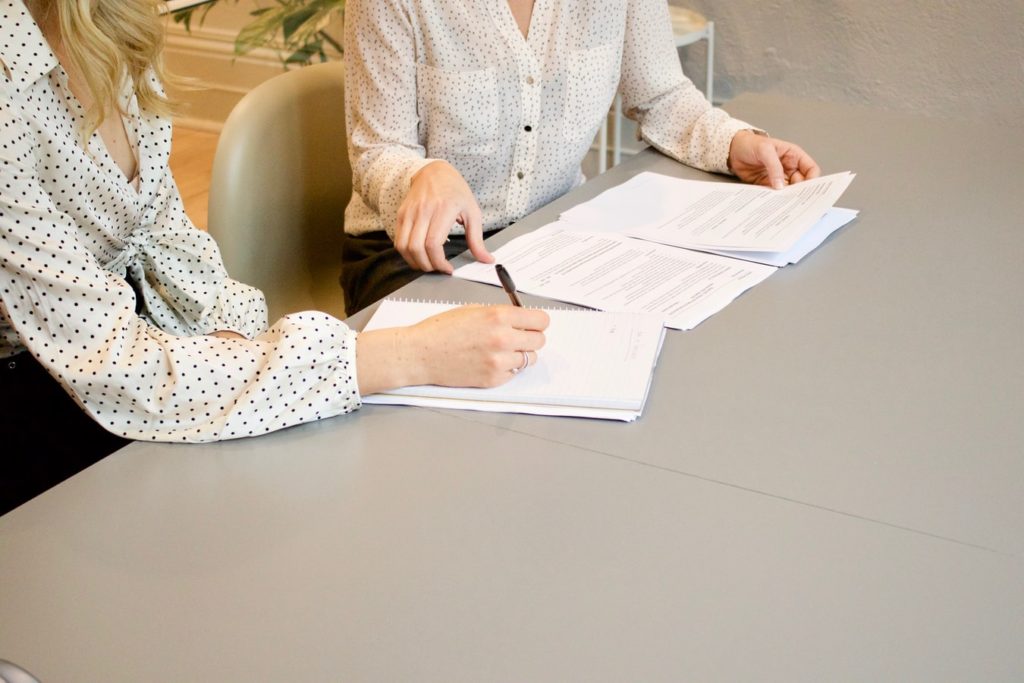 Deux jeunes femmes signant des documents.