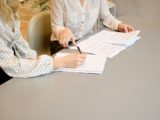 Deux jeunes femmes signant des documents.