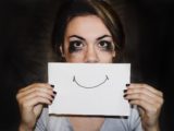 Une femme battue au foyer esquissant un sourire sur du papier placé sur sa bouche.