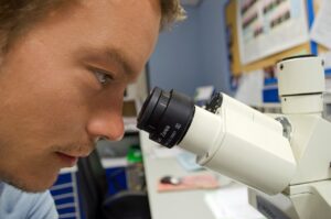 Un jeune laboratin regardant dans un microscope.